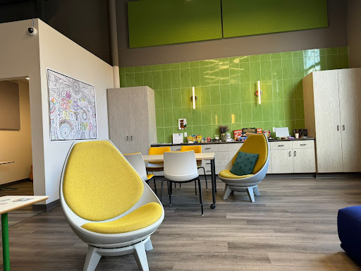 The meeting area of Upstreet with colorful chairs, games, and puzzles accessible to all.